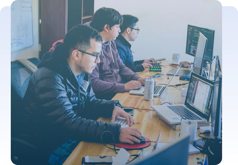 Software developers working together at computers in a modern office.