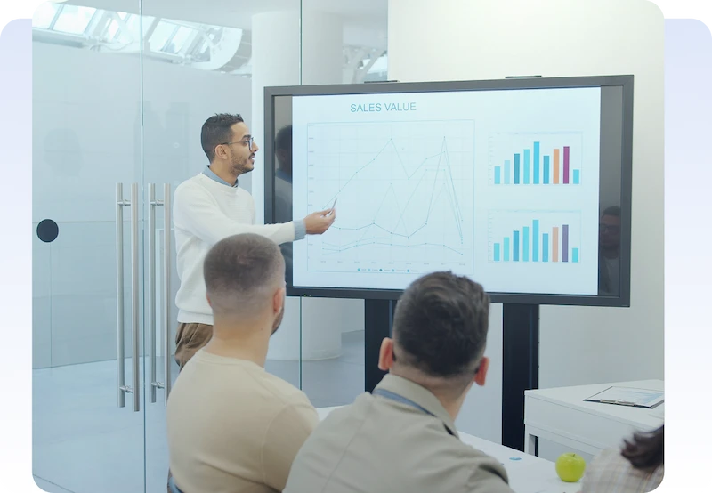 Investor Technical Advisory Photo Presenter explaining sales charts to colleagues during a business meeting.