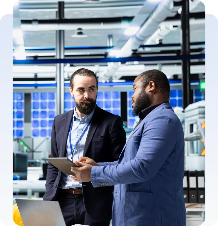 Two business professionals discussing information on a tablet in a technology facility.