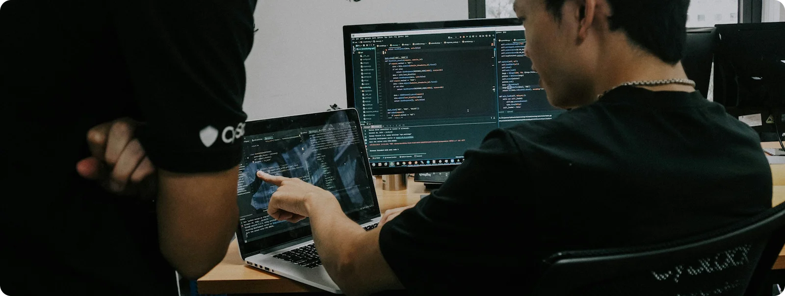 Software developers reviewing code on multiple screens.